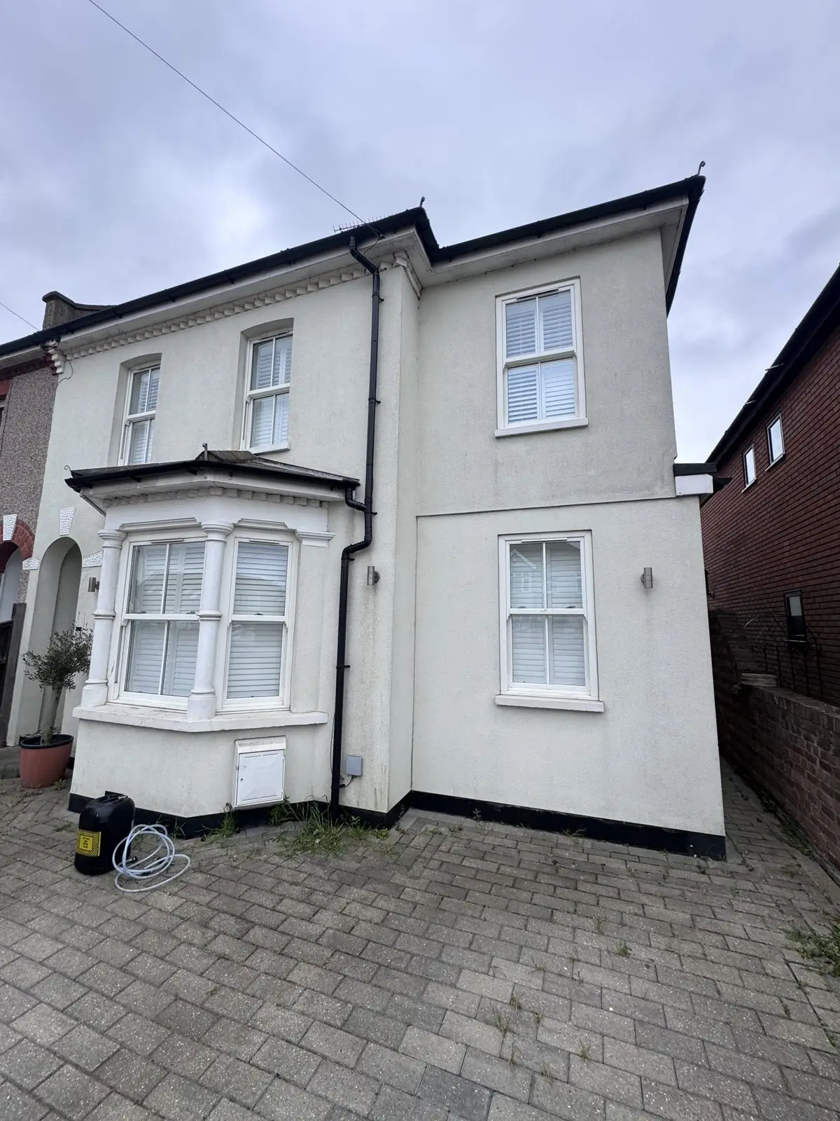 House render before soft washing, streaked with algae and weathering